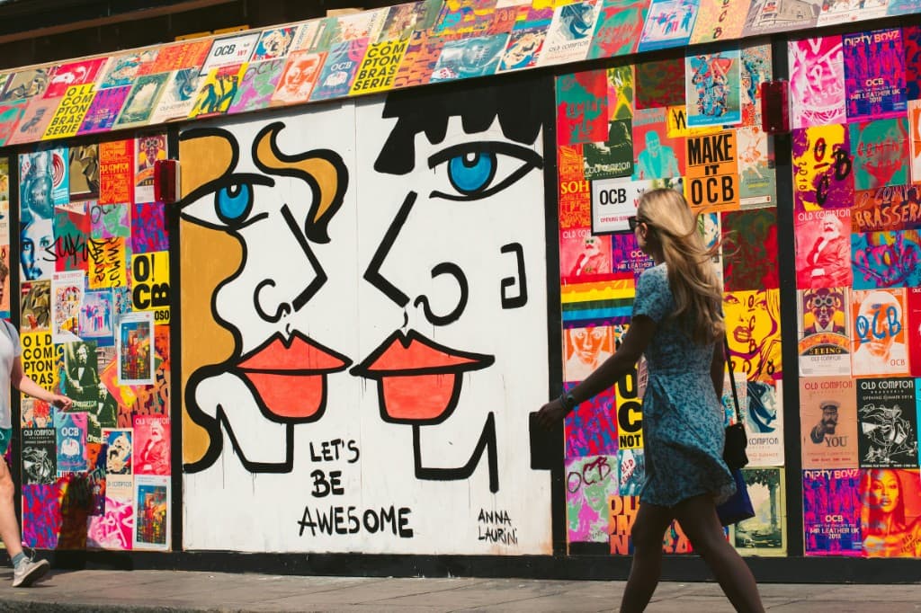 Mural colorido numa parede de rua, com uma mulher passando